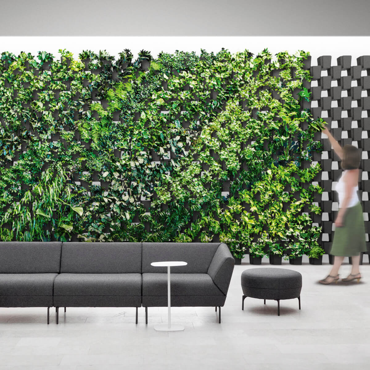 Grüne Pflanzenwand aus modularen FlexiFlora-Töpfen in modernem Innenraum mit Sitzmöbeln