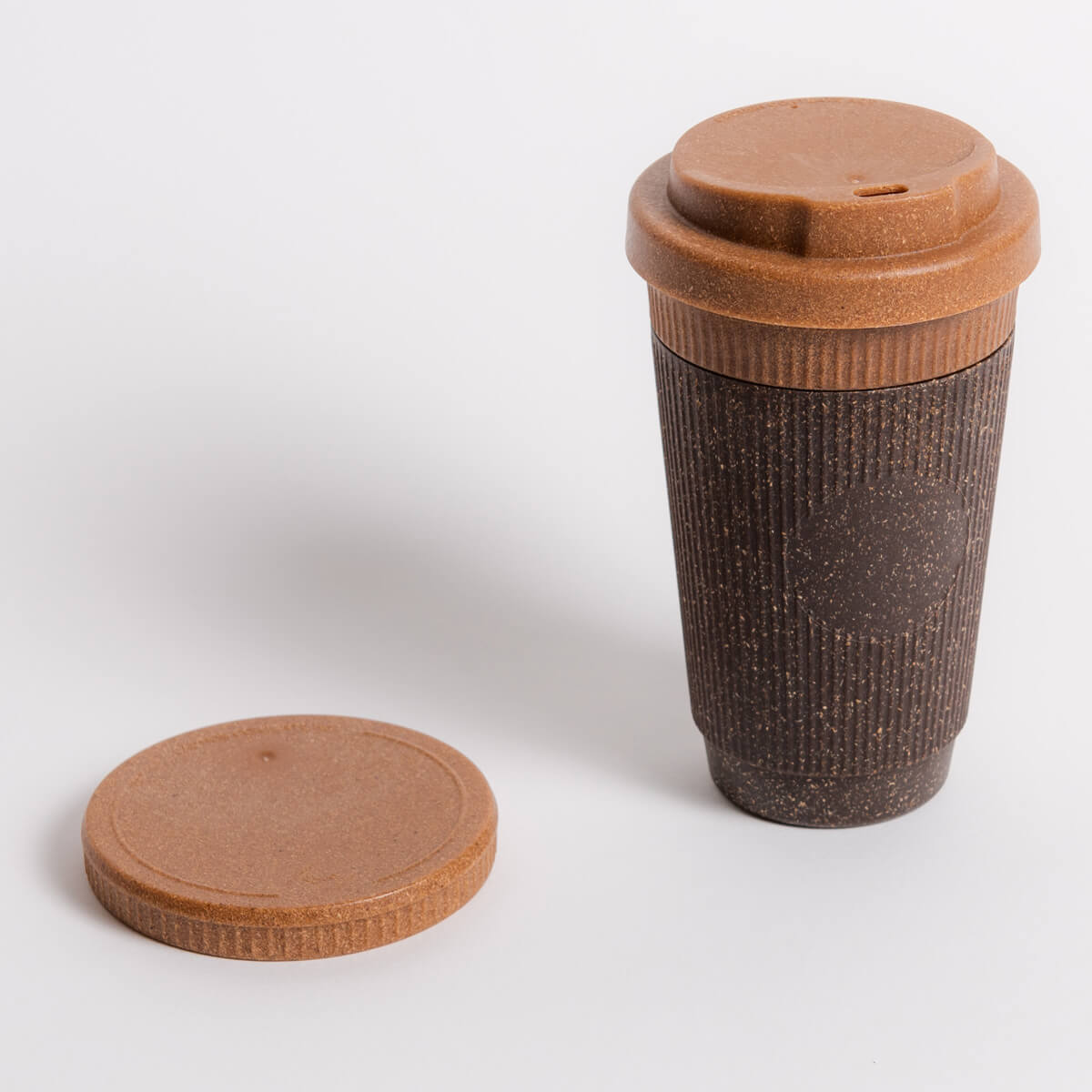 Wiederverwendbarer Kaffeebecher von Kaffeeform in der Variante Refined Nutmeg mit braunem Deckel und zusätzlichem Deckel auf weißem Hintergrund.