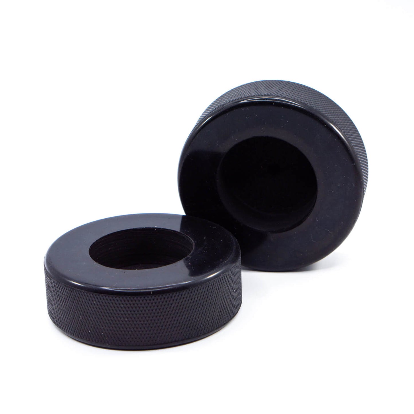 Zwei schwarze Teelichthalter aus recycelten Eishockey-Pucks auf weißem Hintergrund – ohne Teelicht.