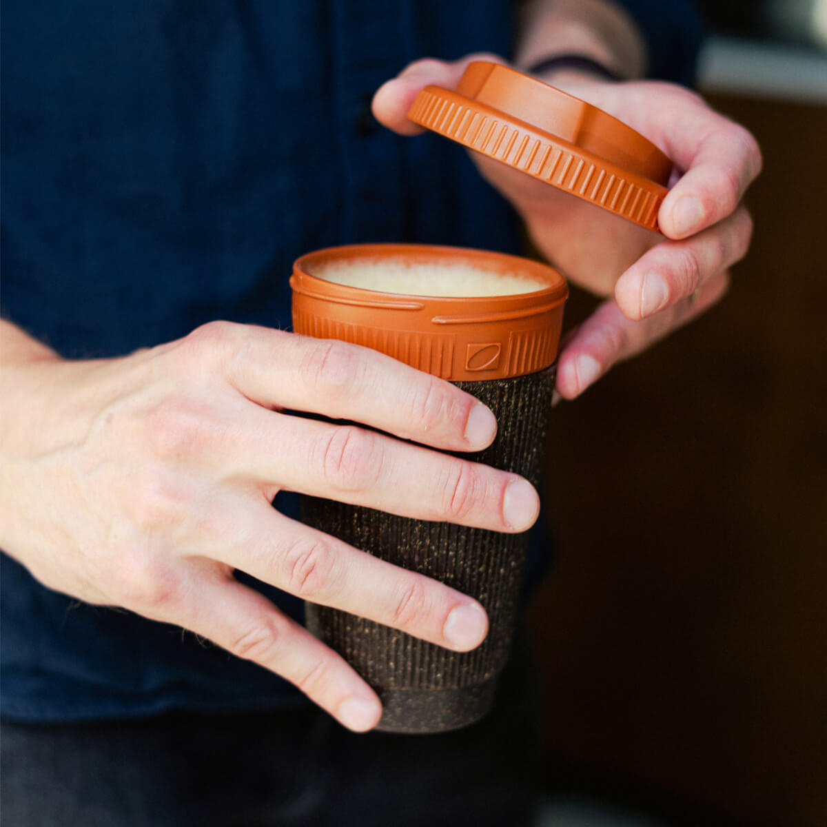 Wiederverwendbarer Coffee-to-go Becher aus Kaffeesatz wird geöffnet – nachhaltiger Becher mit Deckel für heißen Kaffee unterwegs.